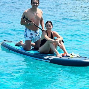 Couple paddleboarding in turquoise Adriatic water.
